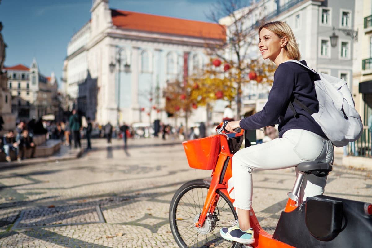Young female tourist riding bicycle by Lisbon, Portugal