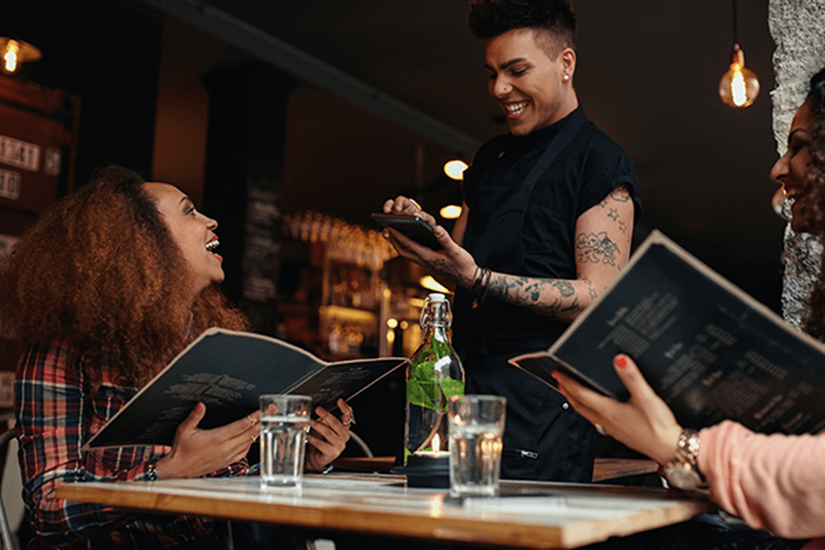 Image of young women placing an order to a waiter in a cafe