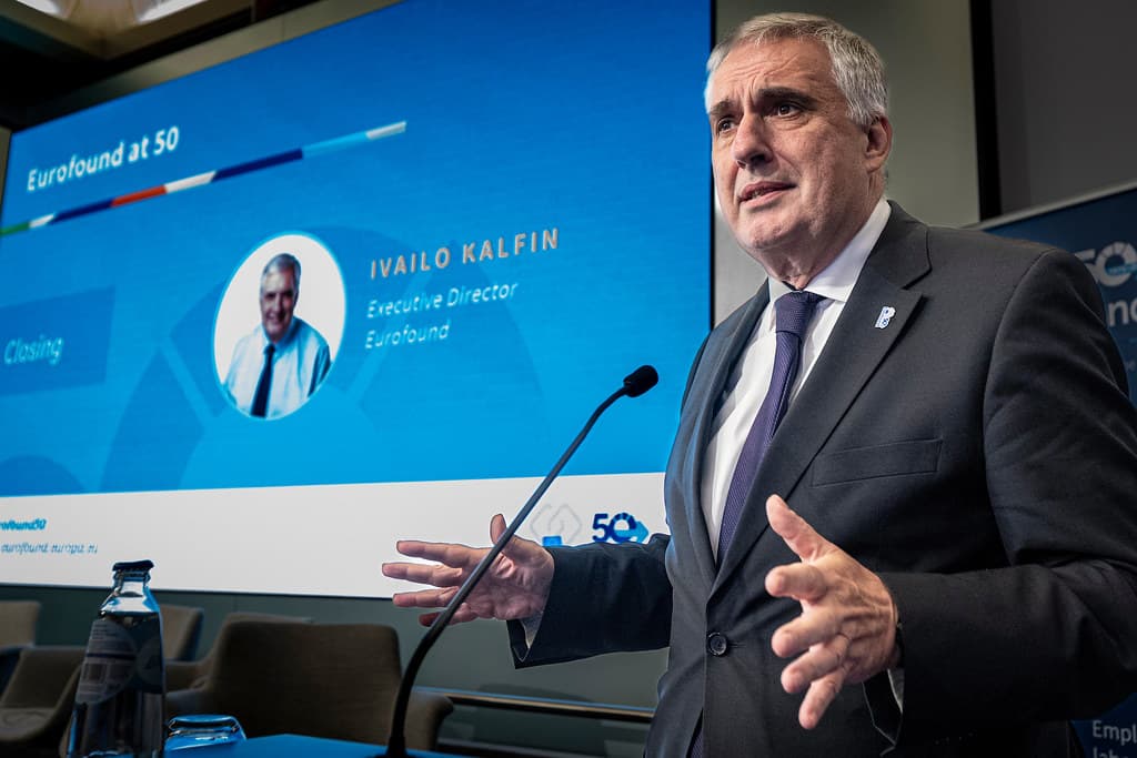 Man speaking at a podium with a presentation slide behind him showing "Eurofound at 50" and "Ivailo Kalfin, Executive Director, Eurofound."